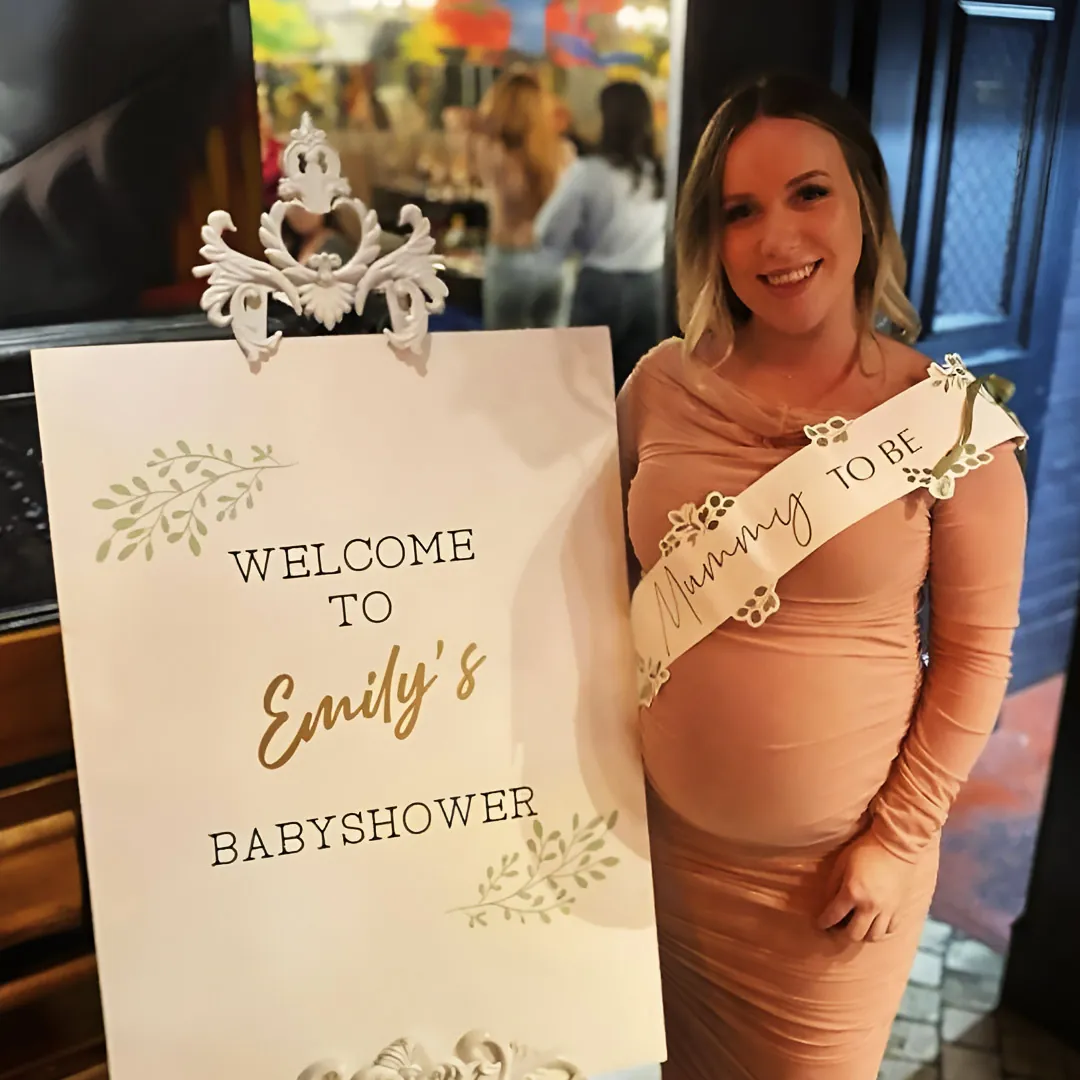 A guest at her baby shower beside a welcome sign