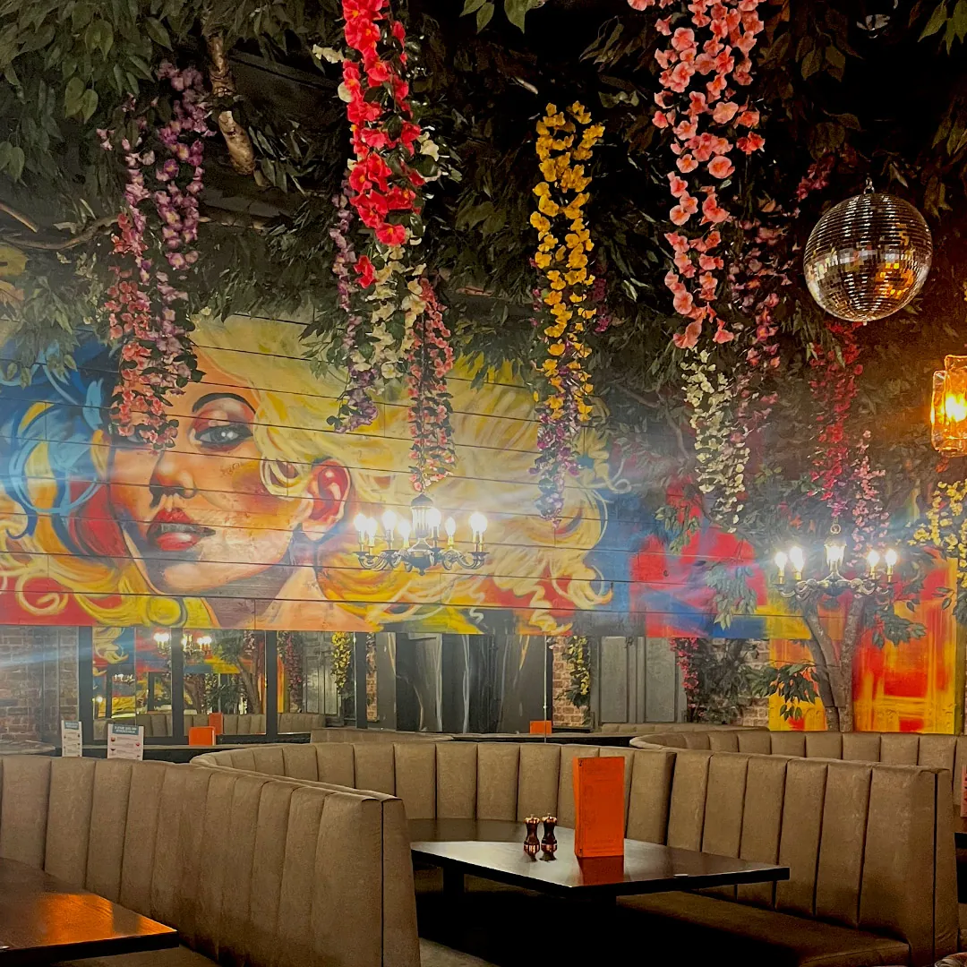 The function room: curved booth seating beneath a painted mural and hanging blossom