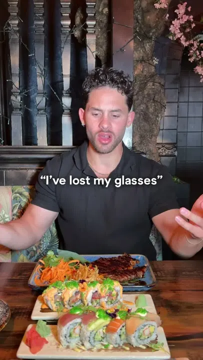 A guest at the table with two sushi rolls and a grilled dish in front of him
